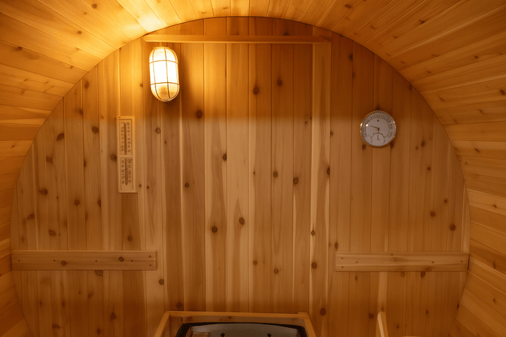 Interior view of a 2-person barrel sauna featuring wooden paneling, lighting, and a clock
