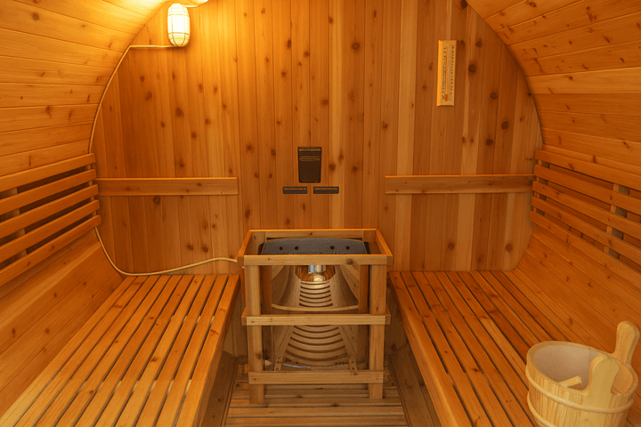 Interior of a SunRay 4-person barrel sauna with wooden benches and a steam heater