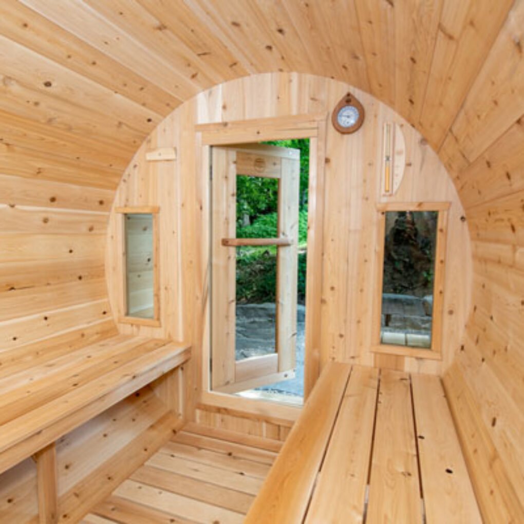 Interior view of a Leisurecraft Backyard Barrel Sauna for Sale featuring natural wood benches and windows