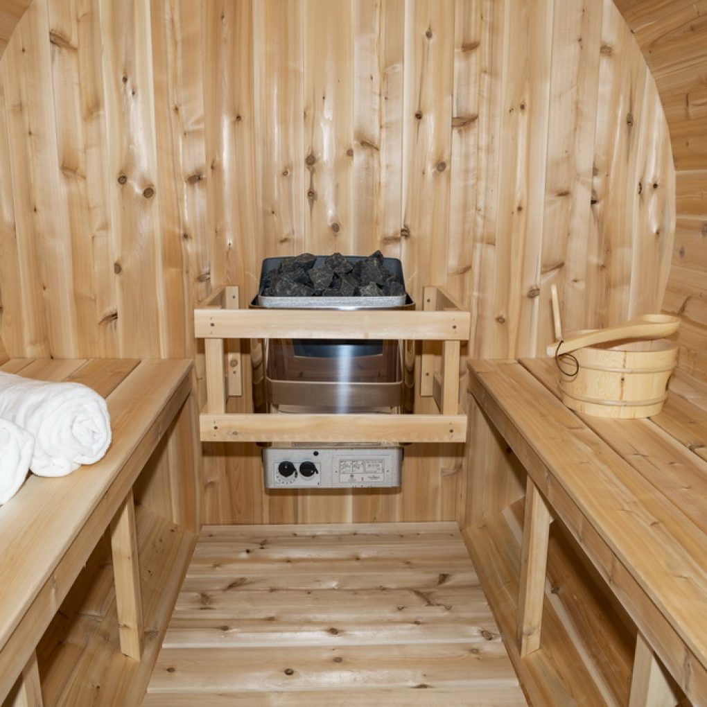 Interior view of Leisurecraft backyard barrel sauna for sale with wooden benches and heater