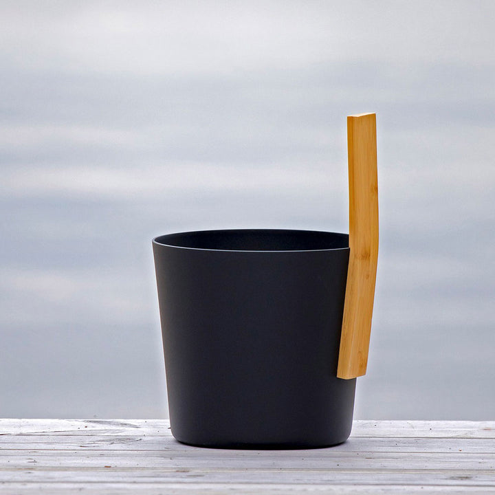 Black sauna bucket with wooden handle, part of KOLO sauna accessories for a modern spa experience
