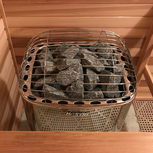 Harvia 12.5 kW luxury sauna heater in stainless steel filled with sauna stones inside wooden sauna