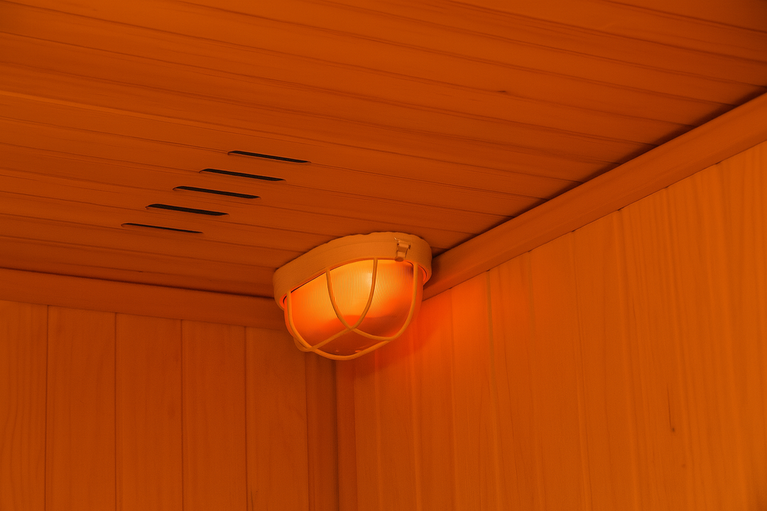 Light fixture installed on ceiling inside SunRay 4-person indoor sauna with wooden panel walls