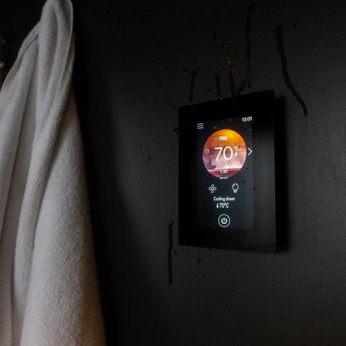 Harvia Fenix WiFi remote control mounted on a wall with a towel hanging nearby