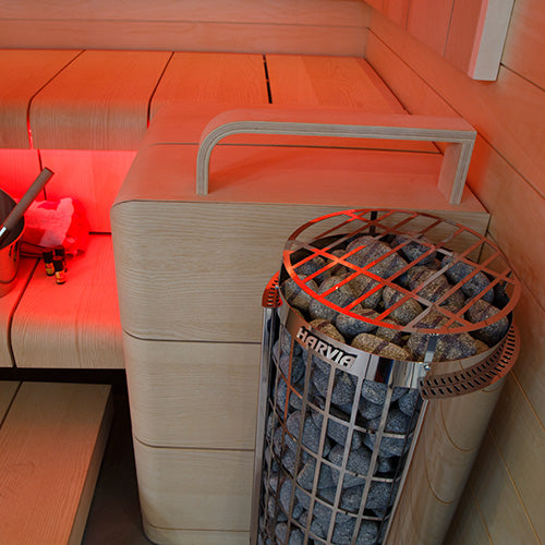 Harvia Cilindro PC90 sauna heater stainless steel stone cylinder with Harvia logo next to wooden bench and bucket