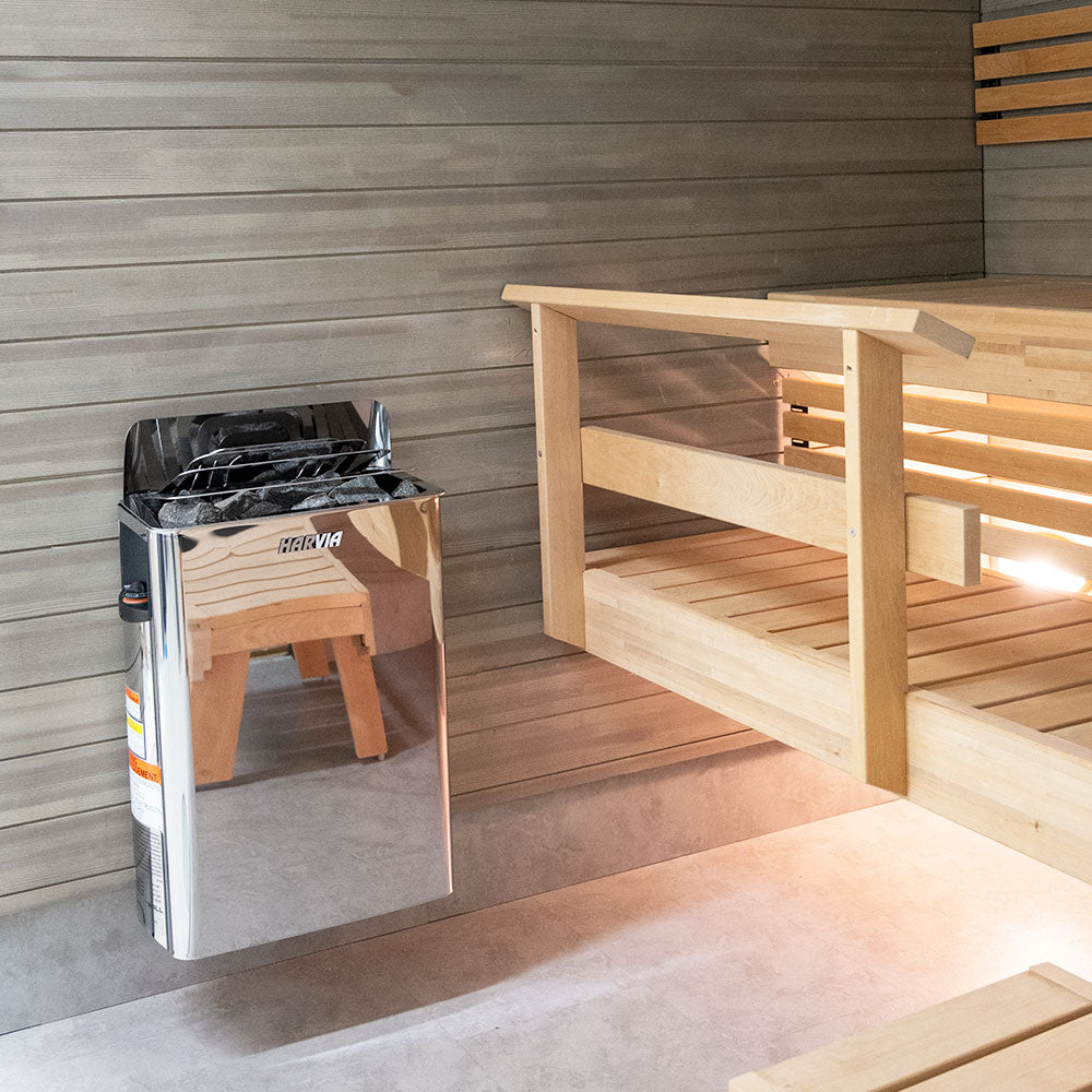 Harvia The Wall electric sauna heater stainless steel wall mounted unit with sauna stones beside wooden bench