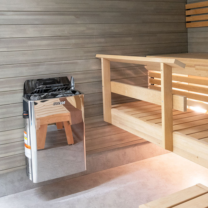 Harvia The Wall electric sauna heater stainless steel wall mounted unit with sauna stones beside wooden bench