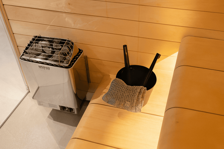 Harvia wall-mounted electric sauna heater with stones and accessories in a wooden sauna setting