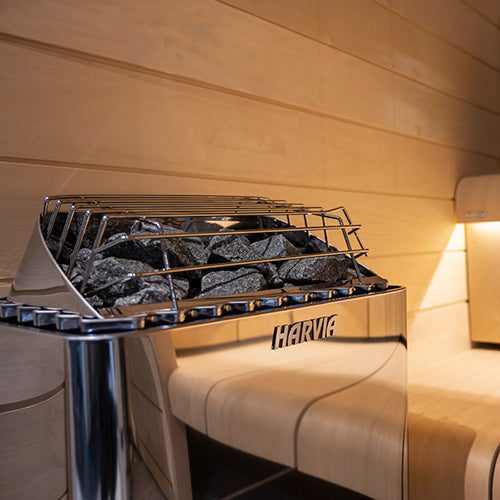 Harvia wall-mounted electric sauna heater stainless steel with sauna stones in wood paneled sauna room