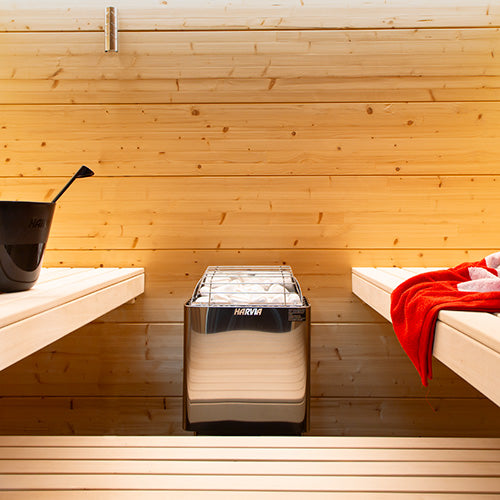 Harvia wall-mounted electric sauna heater installed between wooden benches in light timber sauna