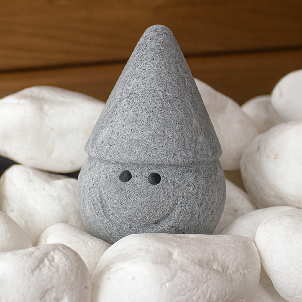 Hukka Tahvo Sauna Elf gray stone figurine with conical hat and smiling face among white sauna stones