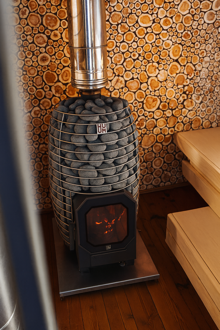 HUUM 8.5kW sauna heater package with stones and wood-burning stove in a wooden sauna room