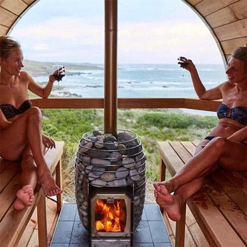 HUUM barrel sauna chimney kit installed with sauna heater stones inside wooden barrel sauna by the ocean