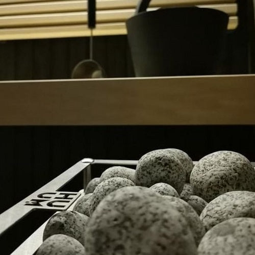 Close-up of HUUM CLIFF 6kW sauna heater with natural sauna stones in a wooden sauna room