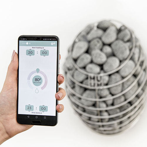 HUUM DROP 4.5kW sauna heater with smart app control on a smartphone in hand
