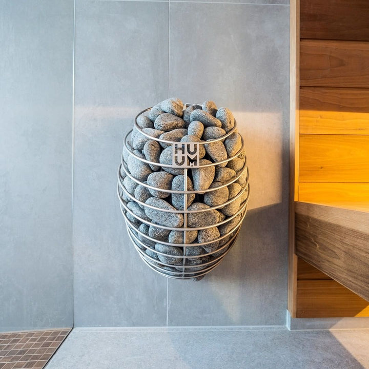 HUUM DROP 4.5kW sauna heater mounted on wall with sauna stones in modern sauna room