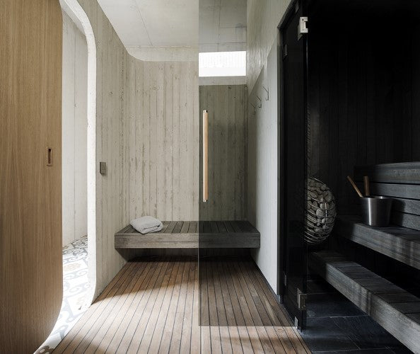Modern sauna interior featuring a HUUM DROP 4.5kW sauna heater with wood benches and stone setup