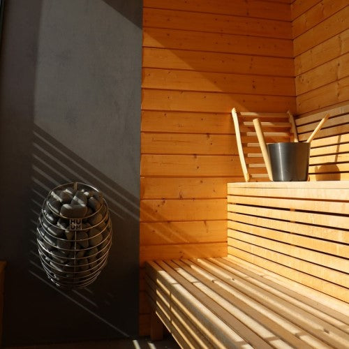 HUUM DROP 9kW sauna heater package installed in wooden sauna room with bench and bucket