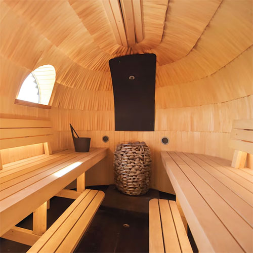 HUUM HIVE electric sauna heater with stone basket inside wooden barrel-style sauna room