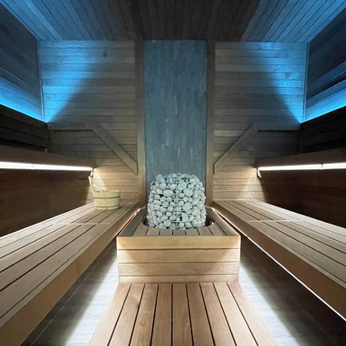 HUUM HIVE electric sauna heater with stones inside modern wooden sauna room with ambient lighting