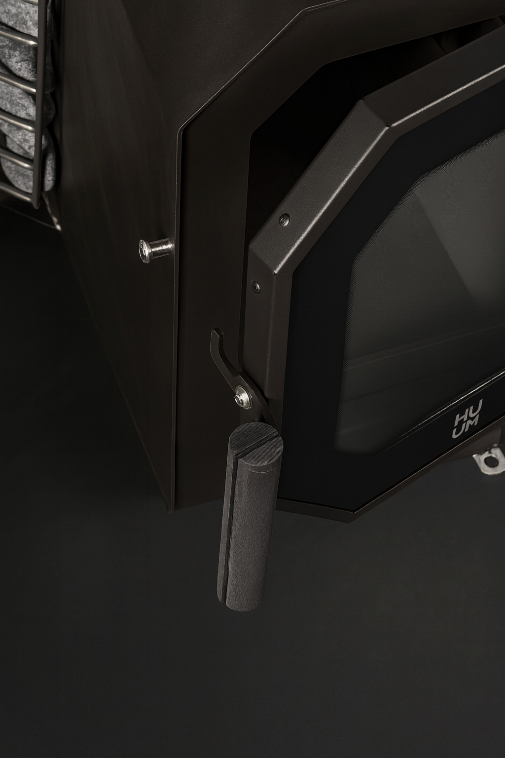 Close-up of black HUUM HIVE Flow Series sauna heater door handle and glass panel