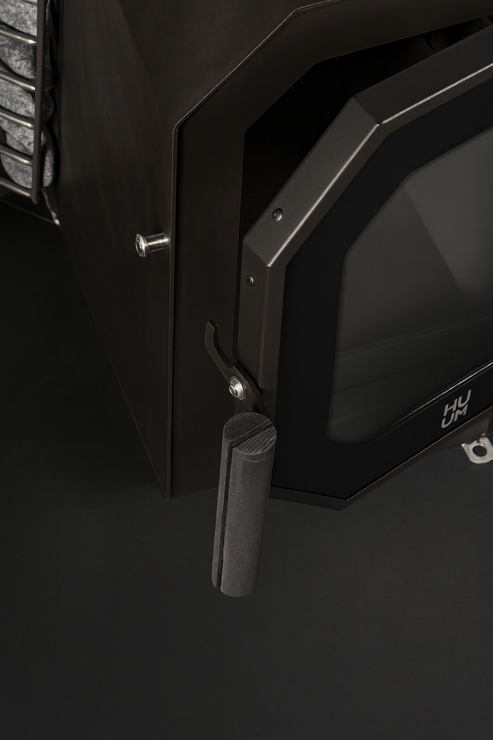 Close-up of black HUUM HIVE Flow Series sauna heater door handle and glass panel