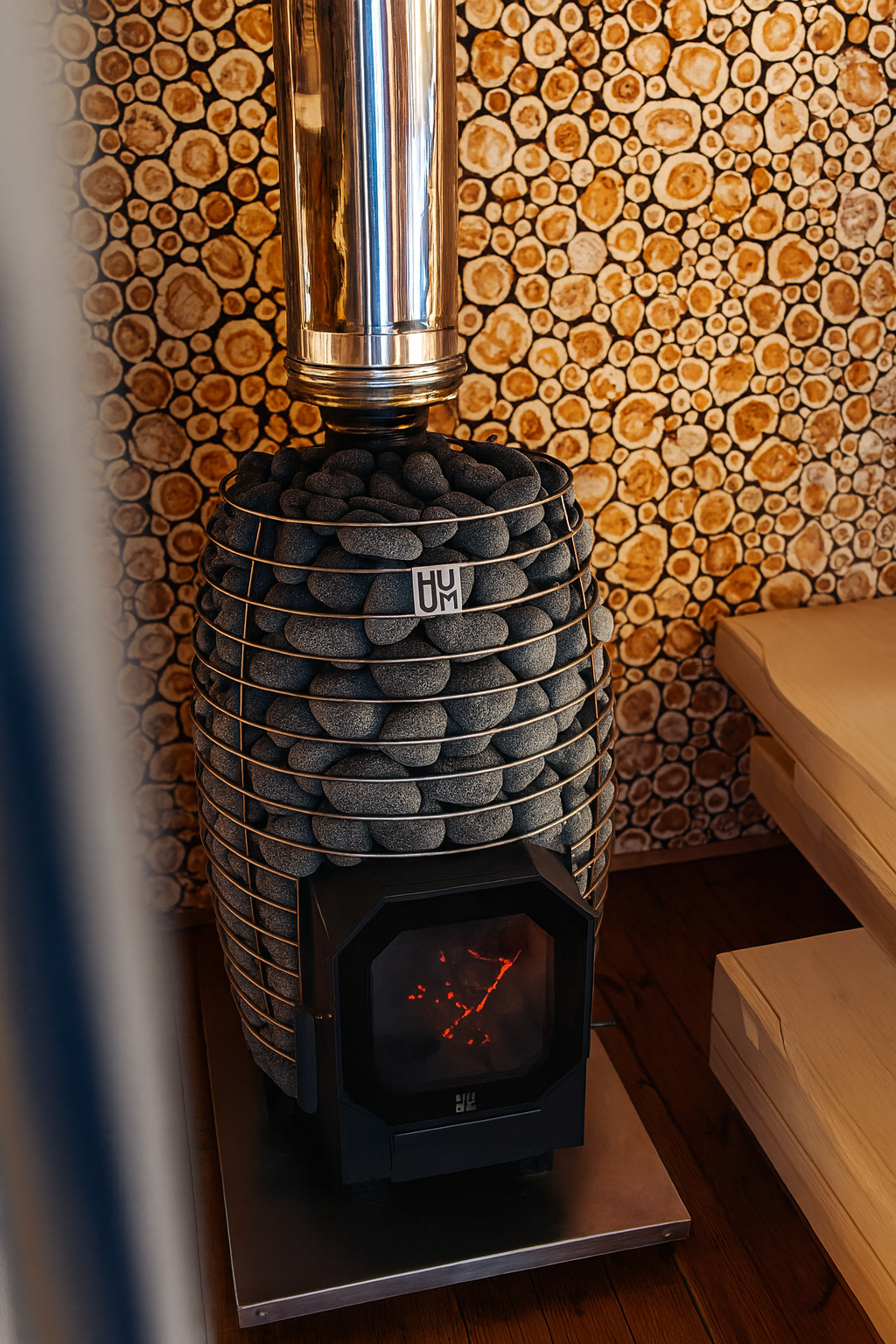 HUUM HIVE Flow Series sauna heater with stacked stones and stainless steel chimney pipe