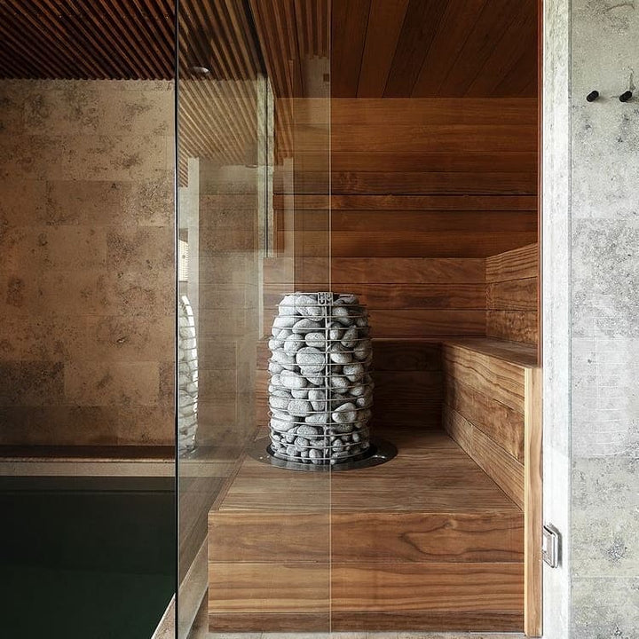 HUUM HIVE Mini 6kW sauna heater stone tower inside a wooden sauna room with glass door