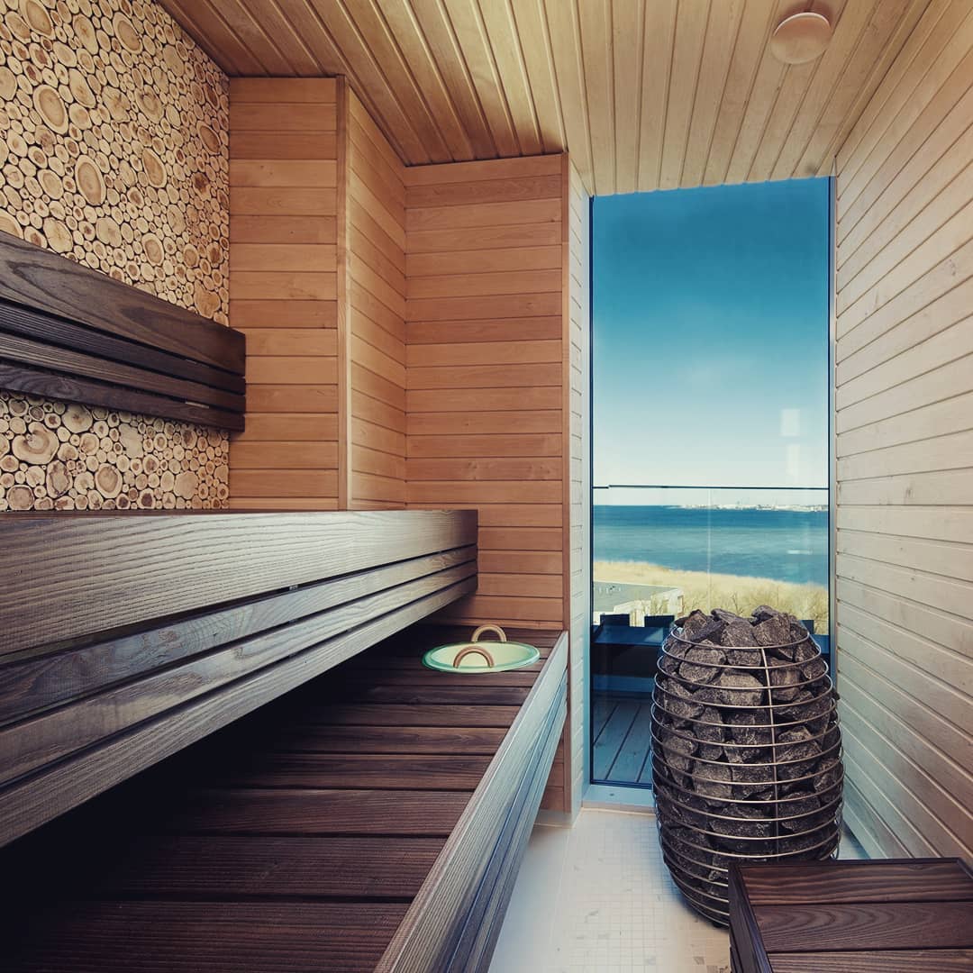 HUUM HIVE Mini 6kW sauna heater inside modern wooden sauna with bench and ocean view