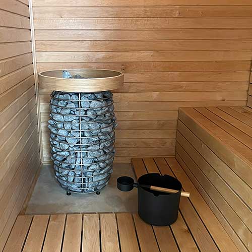HUUM HIVE Mini 6kW sauna heater with stone-filled metal frame in wooden sauna interior