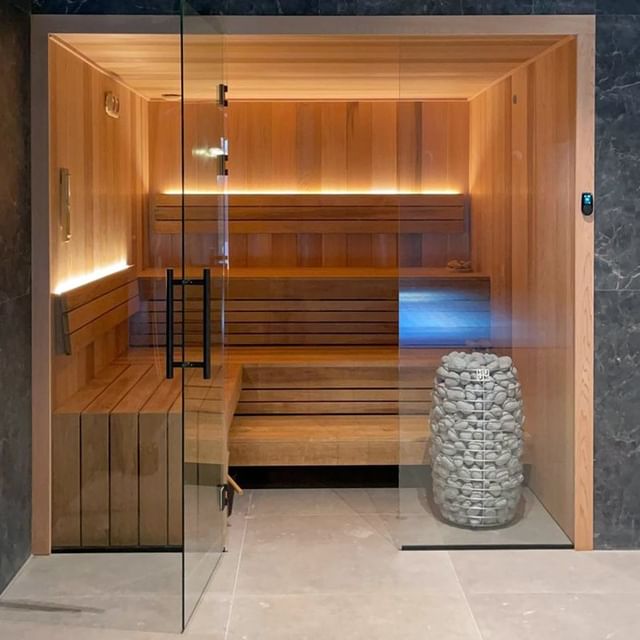 HUUM HIVE Mini 9kW electric sauna heater inside modern wooden sauna with glass door