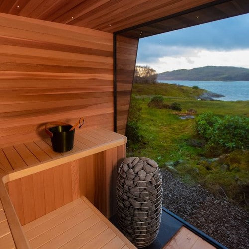 HUUM HIVE Mini 9kW electric sauna heater with stones inside modern wooden sauna overlooking lake