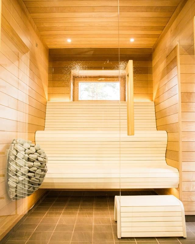HUUM DROP 4.5kW sauna heater. Wall mounted stone unit in light wood sauna with bench and glass door