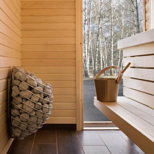 HUUM DROP 4.5kW sauna heater. Wall mounted stone heater in a light wood sauna with bench and ladle