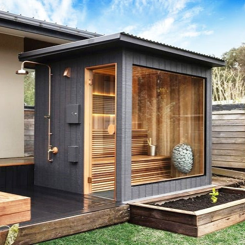 HUUM DROP 4.5kW sauna heater visible inside modern outdoor HUUM sauna cabin with glass wall and wooden benches