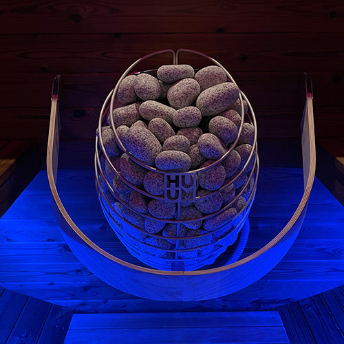 HUUM DROP 4.5kW sauna heater stainless steel stone basket with wooden safety railing in blue lit sauna