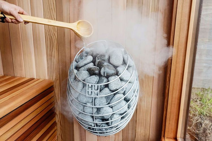 HUUM DROP 6.0kW sauna heater wall mounted stone basket with wooden ladle pouring water and rising steam