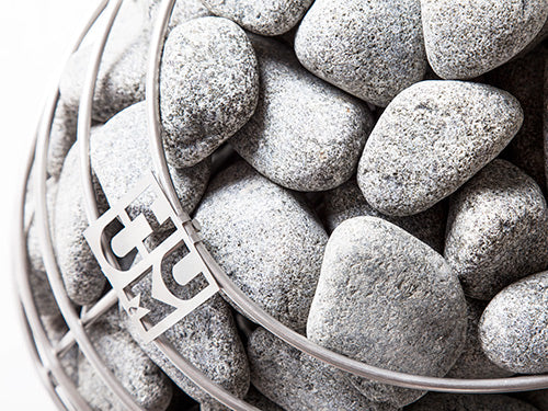 HUUM sauna heater stones inside a metal basket with HUUM logo for sauna heating