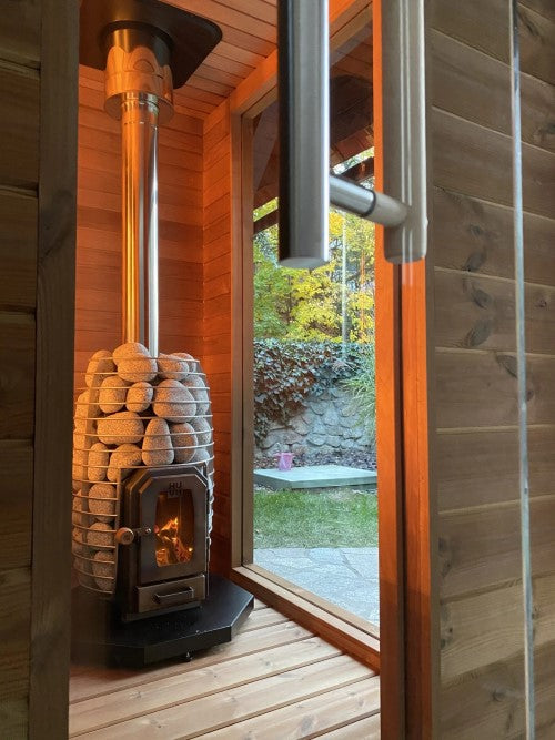 HUUM thru-ceiling chimney kit installed on wood-burning stove inside wooden sauna room