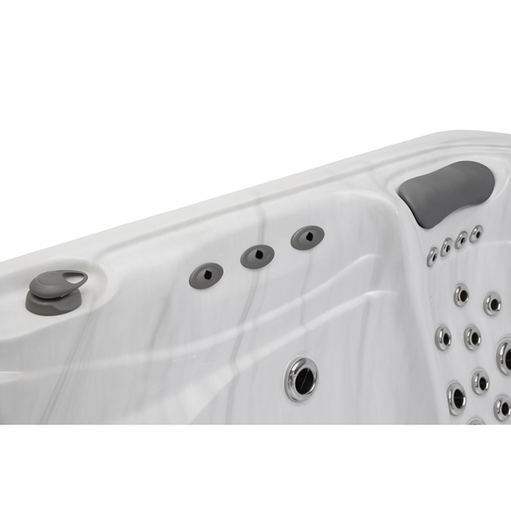 Close-up of white Infinity Elite Series hot tub by Luxury Spa featuring multiple jets and headrest