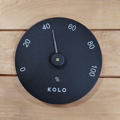 KOLO hygrometer for sauna with black dial and white humidity markings on wooden background