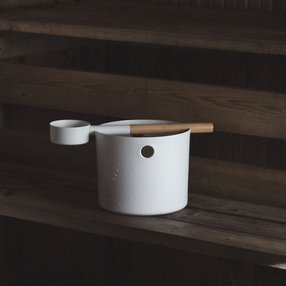White KOLO sauna accessories bucket and ladle with wooden handle on wooden sauna bench