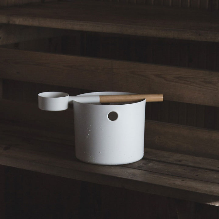 White KOLO sauna accessories bucket and ladle with wooden handle on wooden sauna bench