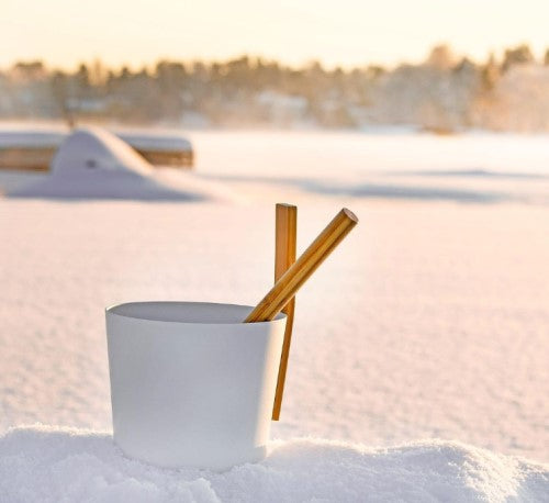 KOLO sauna bucket and ladle set placed on snow with a blurred winter background
