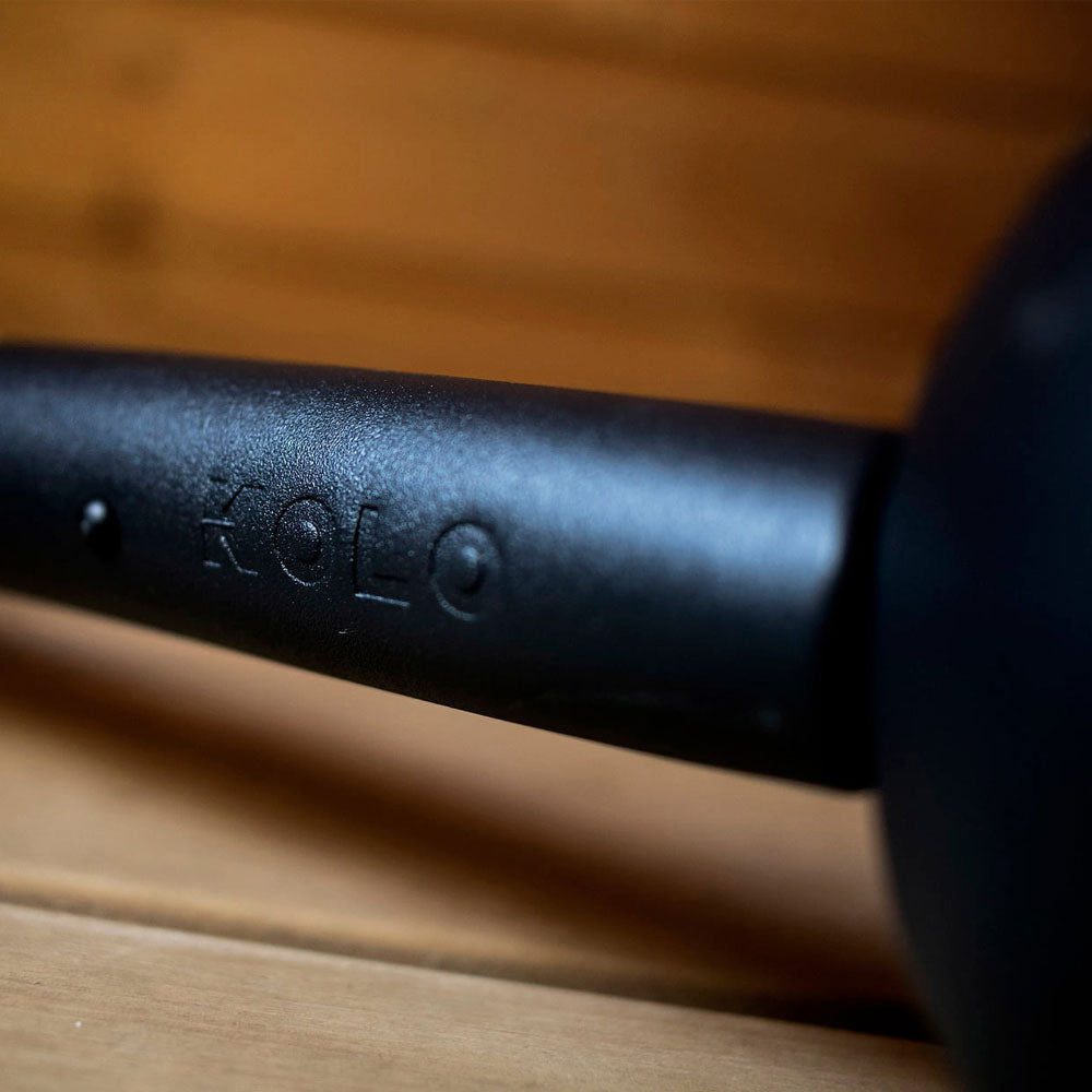 Close-up of KOLO sauna ladle with wood handle black embossed logo on smooth wooden background