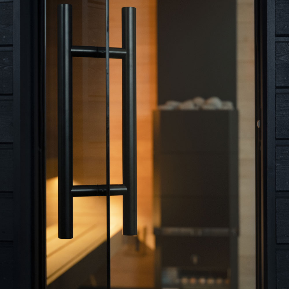 Close-up of modern black handle on glass door of SaunaLife luxury backyard sauna