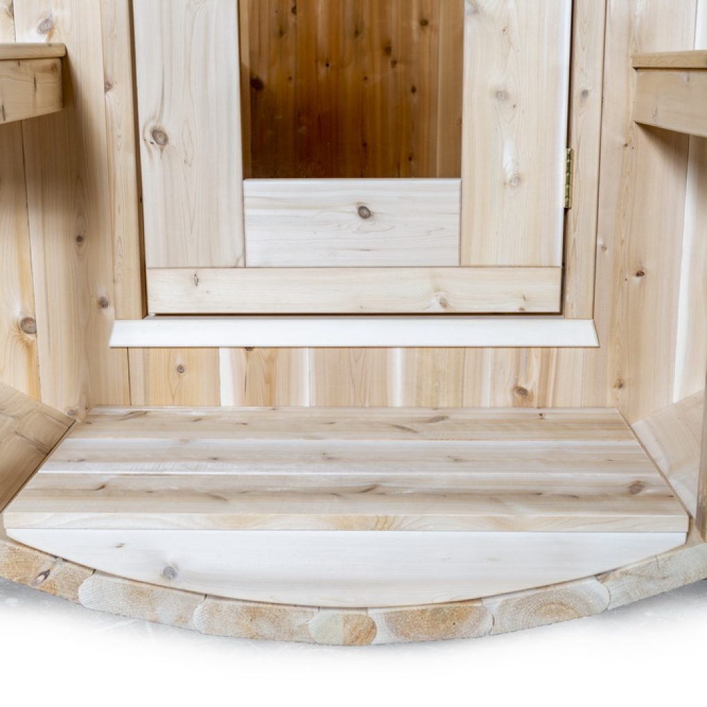 Interior view of a luxury barrel sauna showcasing natural wood finishes and a welcoming entryway