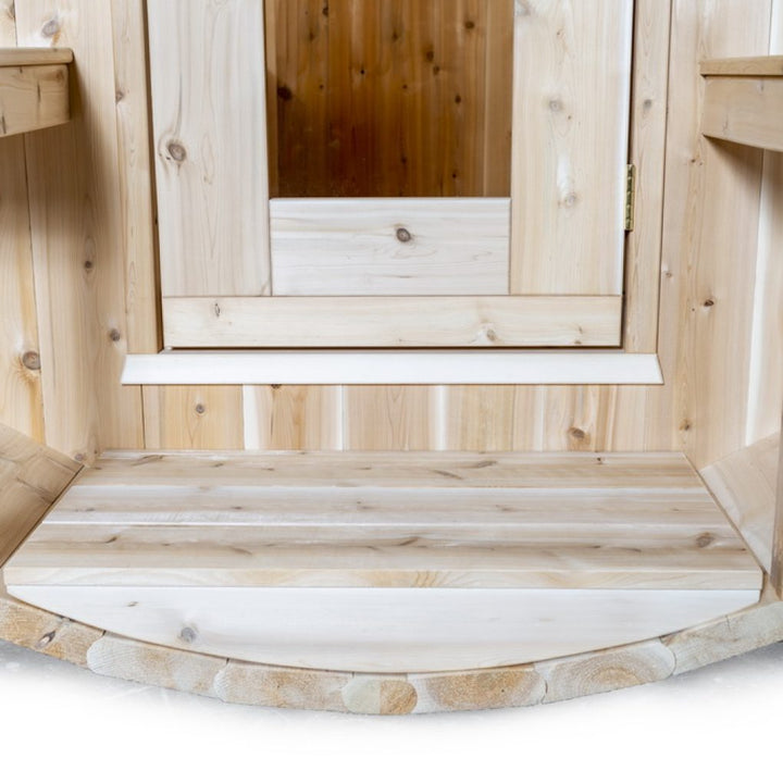 Interior view of a luxury barrel sauna showcasing natural wood finishes and a welcoming entryway