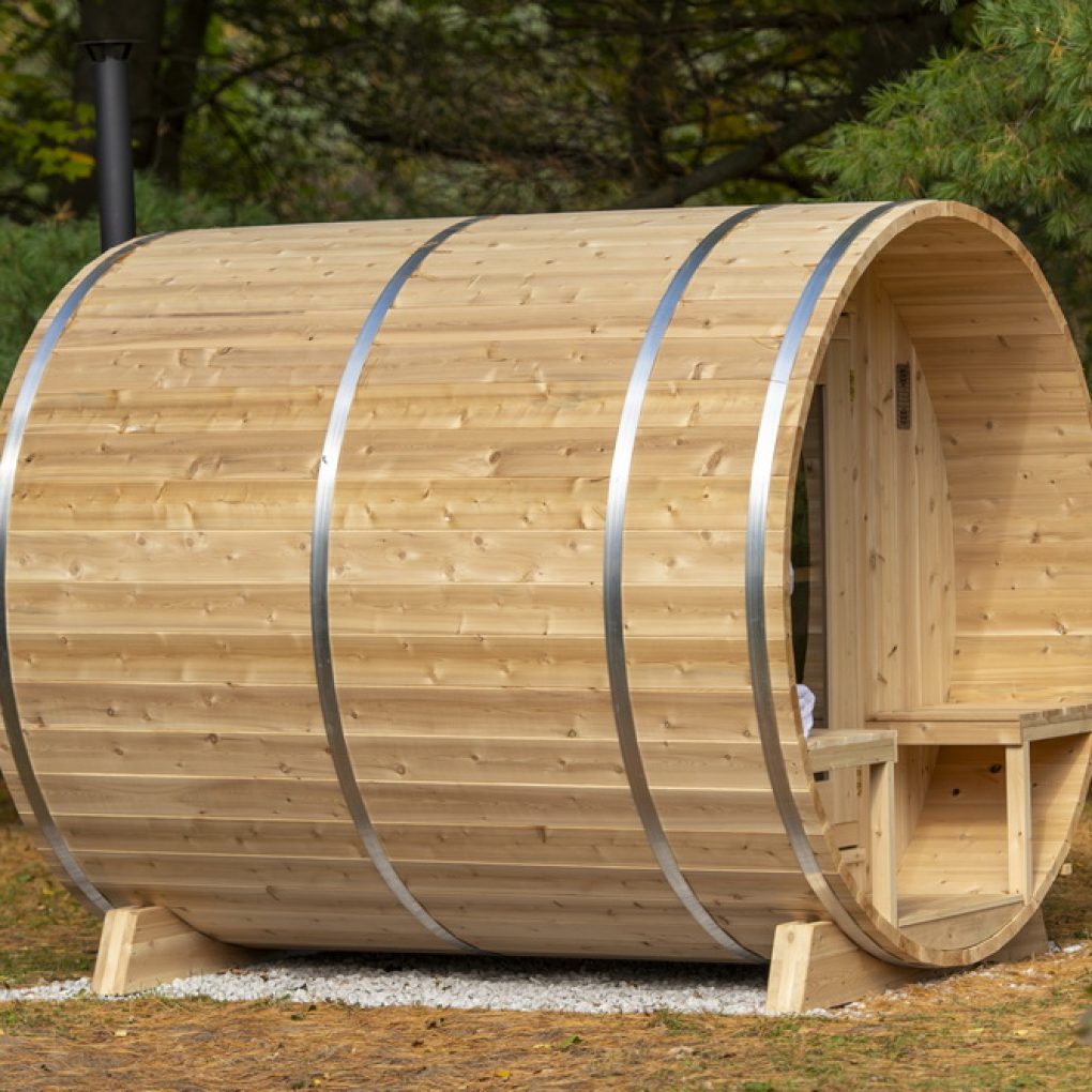 Leisurecraft luxury barrel sauna made of natural wood with metal bands and front seating area outdoors