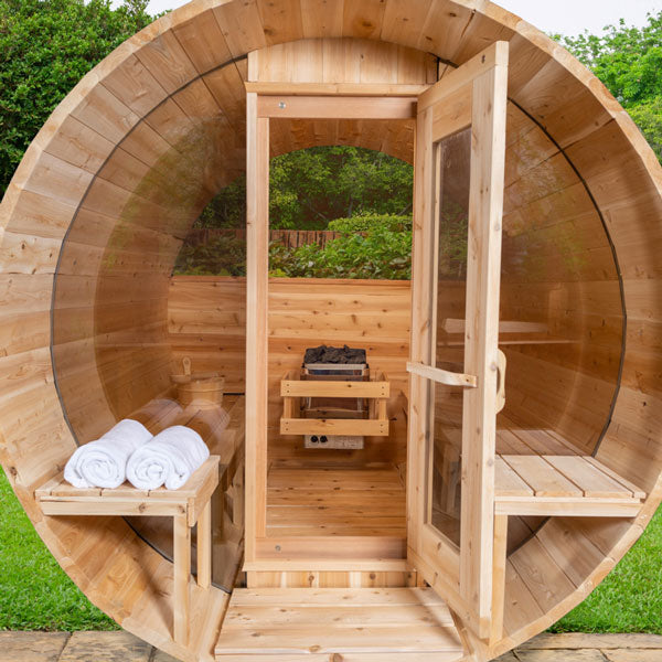 Leisurecraft luxury barrel sauna with wooden exterior and glass door, showing interior with benches and sauna heater